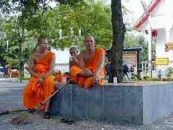 monks sitting resting outside wat pra thong temple in phuket, thailand